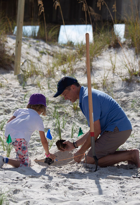 Fabien Cousteau teaching a child how to plant a sea oat